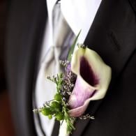 White and purple calla lily boutonniere pinned to a black suit lapel