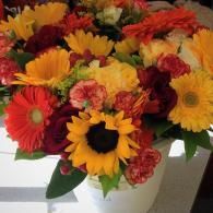 Mixed bouquet of red, yellow, and orange flowers in a white vase