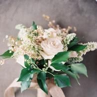 Bouquet of white roses and greenery with beige ribbon on a soft gray background