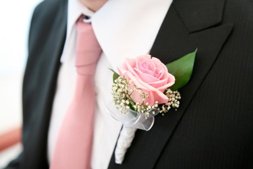 Pink boutonniere on a black suit with a pink tie and white shirt
