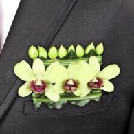 Black suit lapel with a pale green floral boutonniere and burgundy accents