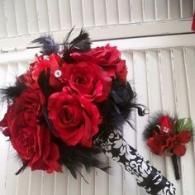 Red and black floral bouquet with roses and feathers on a white shuttered wall