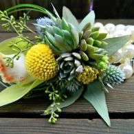Green and yellow floral arrangement with textured blooms on a wooden surface