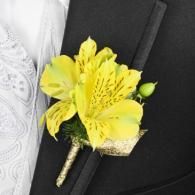 Yellow flower boutonniere pinned to a black suit lapel with a white shirt visible