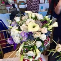 Bouquet of white, purple, and green flowers arranged in a decorative basket