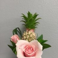 Pink rose bouquet with a pineapple centerpiece against a gray wall