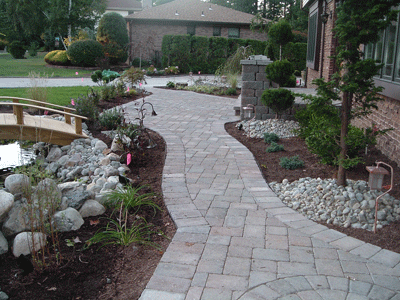 A walkway leading to a house with a bridge over a pond