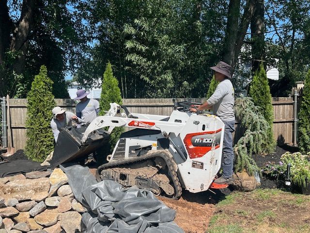 A man is driving a small white bulldozer in a backyard.