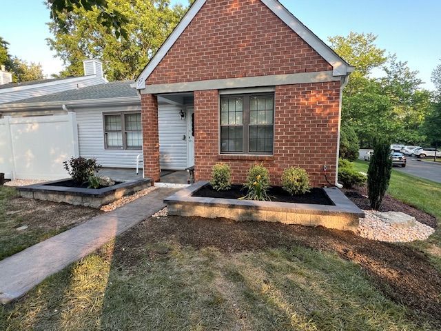 A brick house with a white trim and a walkway leading to it.