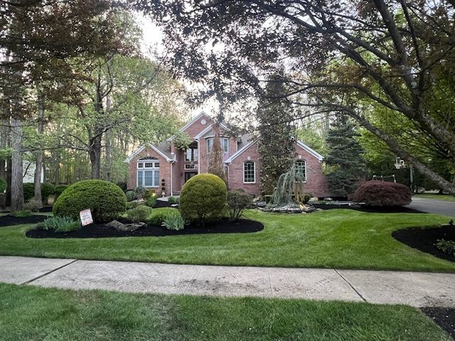 A large brick house with a lush green lawn in front of it