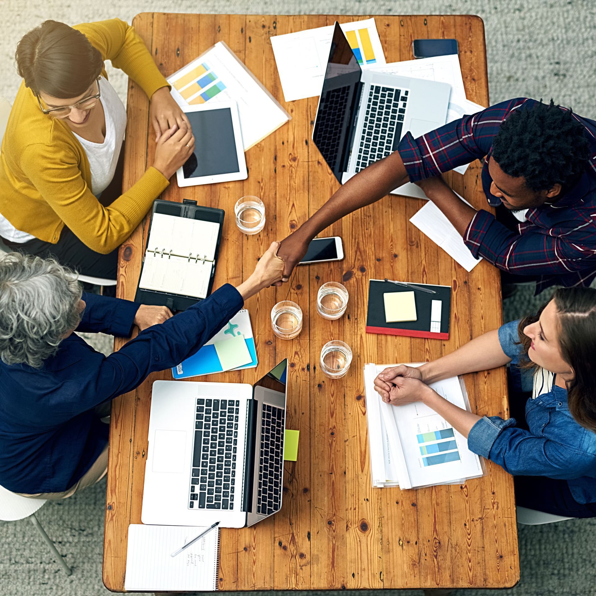 Une équipe réunie autour d'une table examine des graphiques et des ordinateurs portables lors d'une réunion d'affaires.