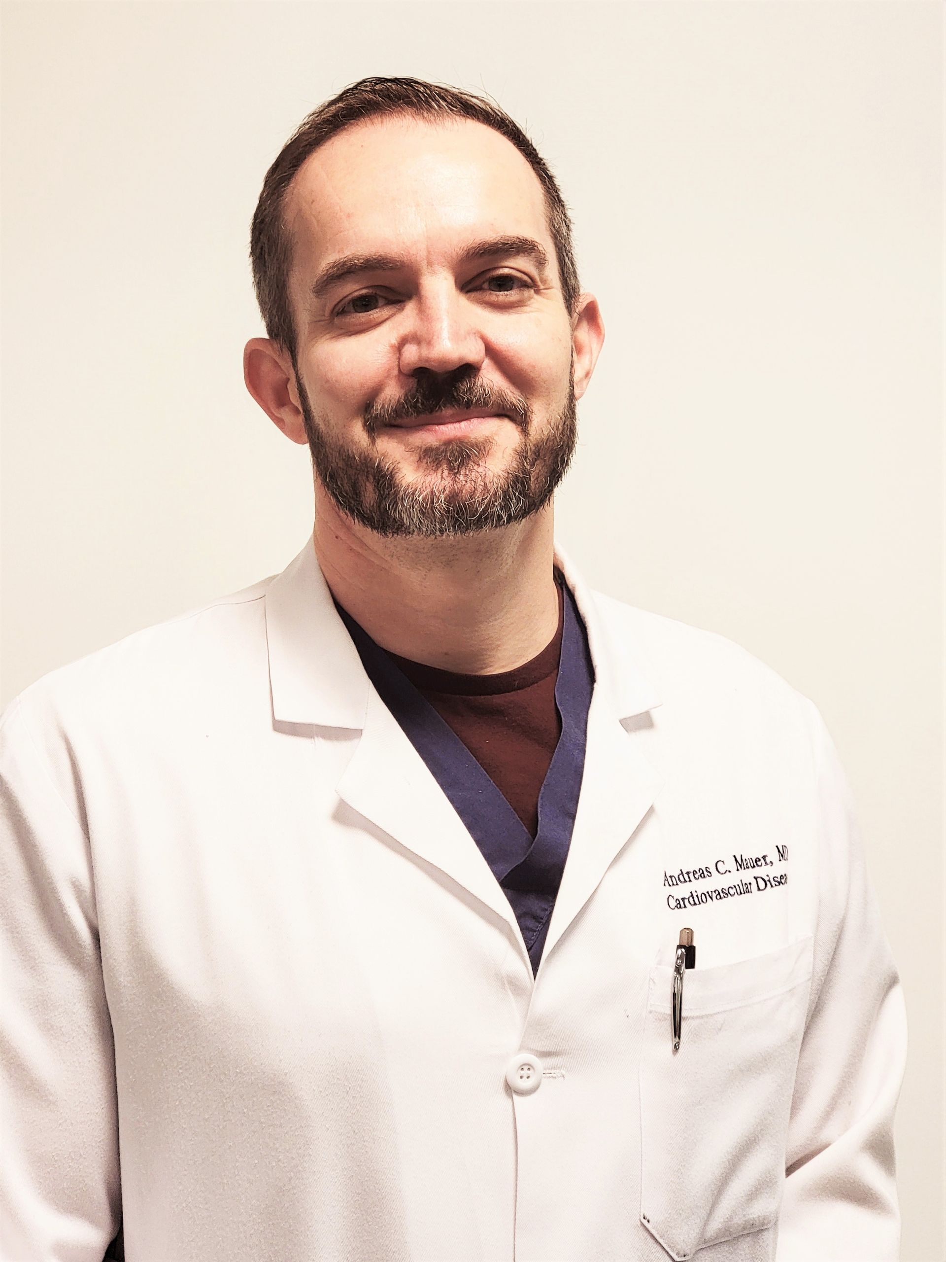 Smiling doctor in a white lab coat against a plain light background