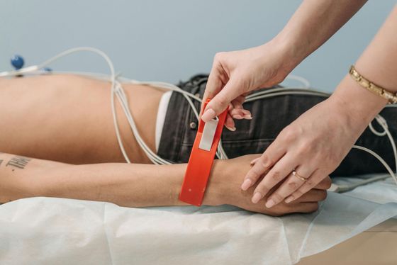 Hand measuring a person’s wrist with a red band in a medical setting