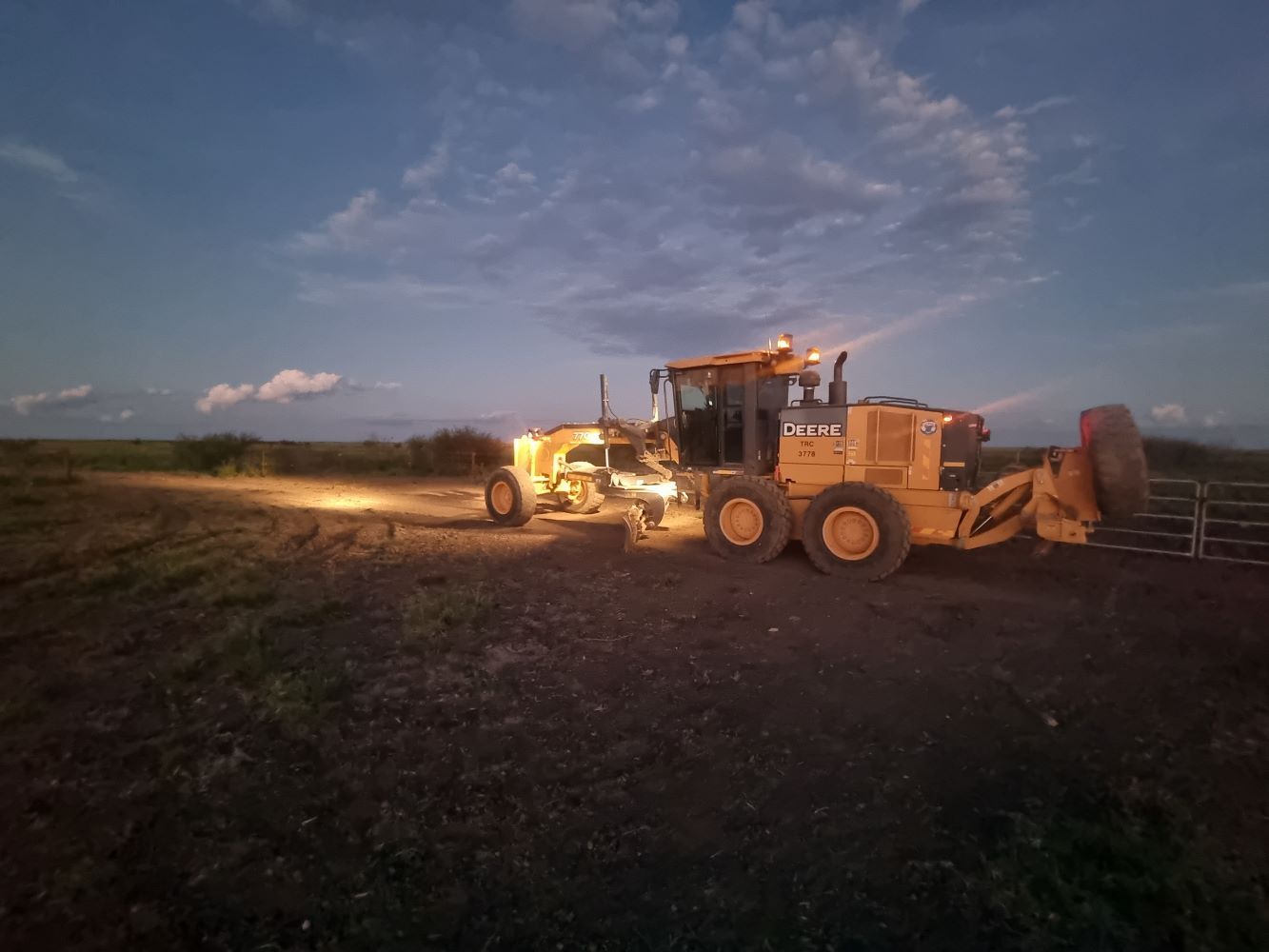 Yellow Tractor is Driving Down a Dirt Road at Night — Burnett Contracting in Cloncurry, QLD