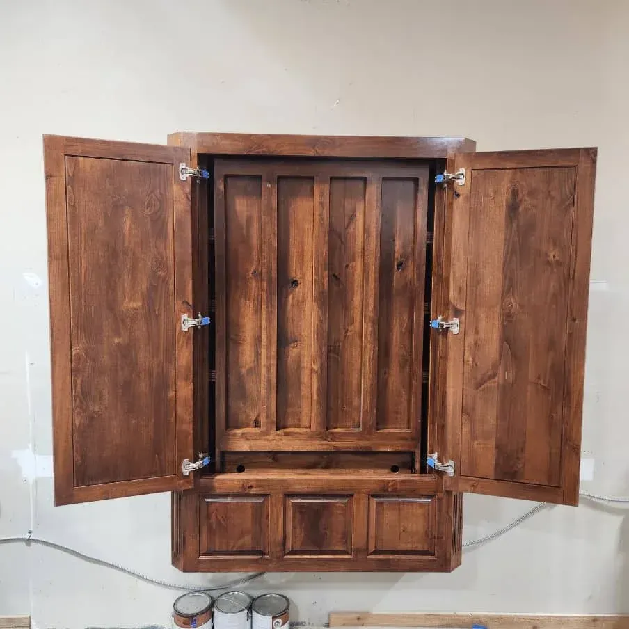 Wooden wall cabinet with open doors, stained brown against a beige wall.
