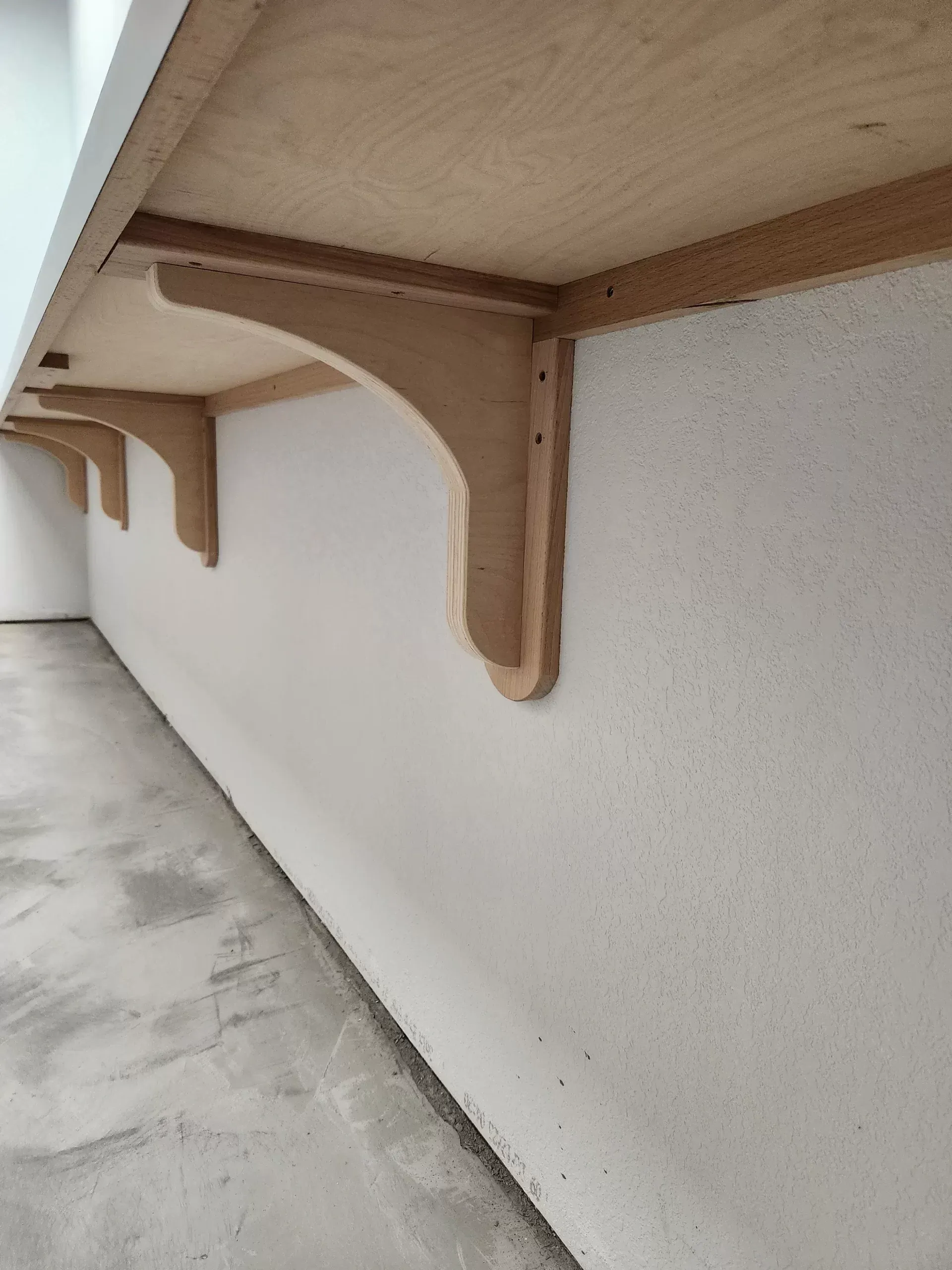 Wooden shelving supported by decorative brackets mounted on a white wall.