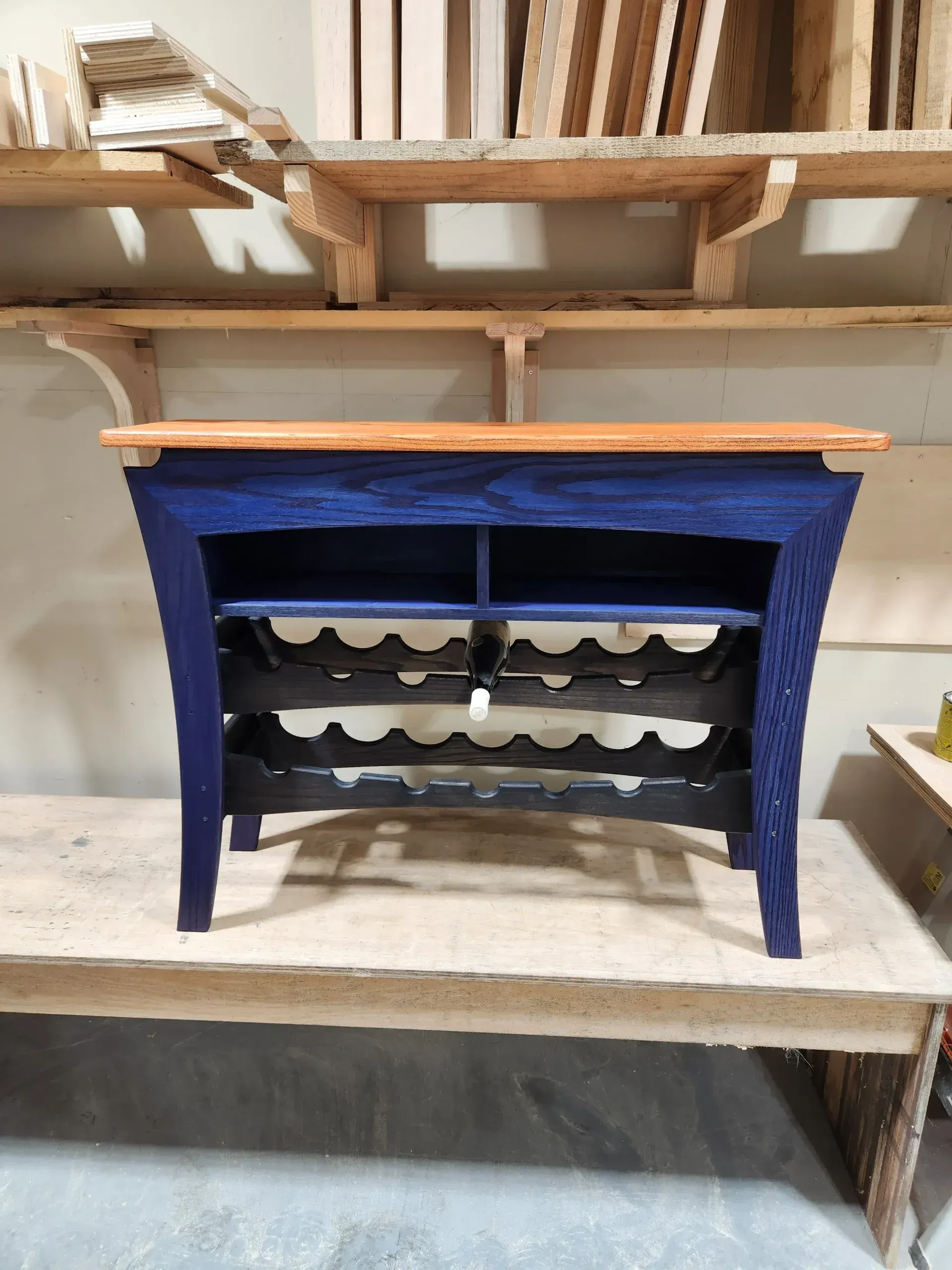Wooden wine rack table in a workshop setting, unfinished.