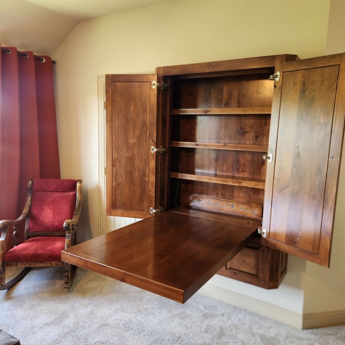 Wooden wall cabinet with open doors, showing interior and hardware, on a painted wall.