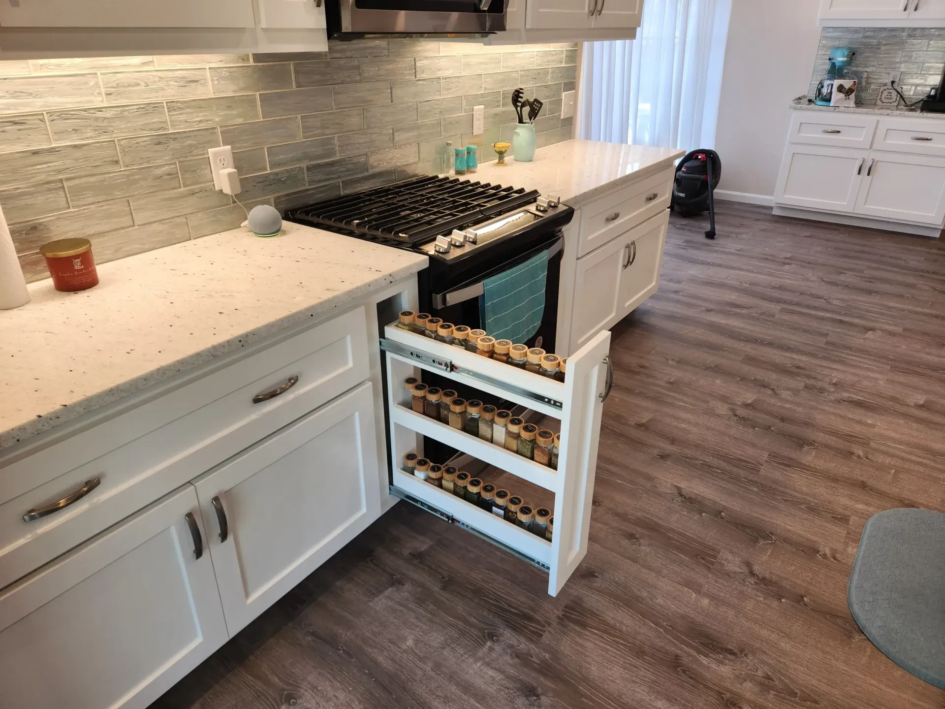 White kitchen with a pull-out spice rack next to the oven.