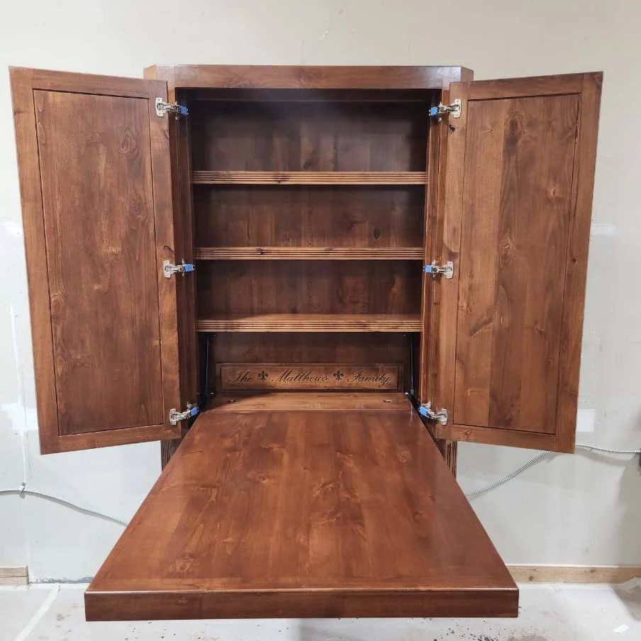 Wooden wall-mounted cabinet with open doors and fold-down table, showing shelves.