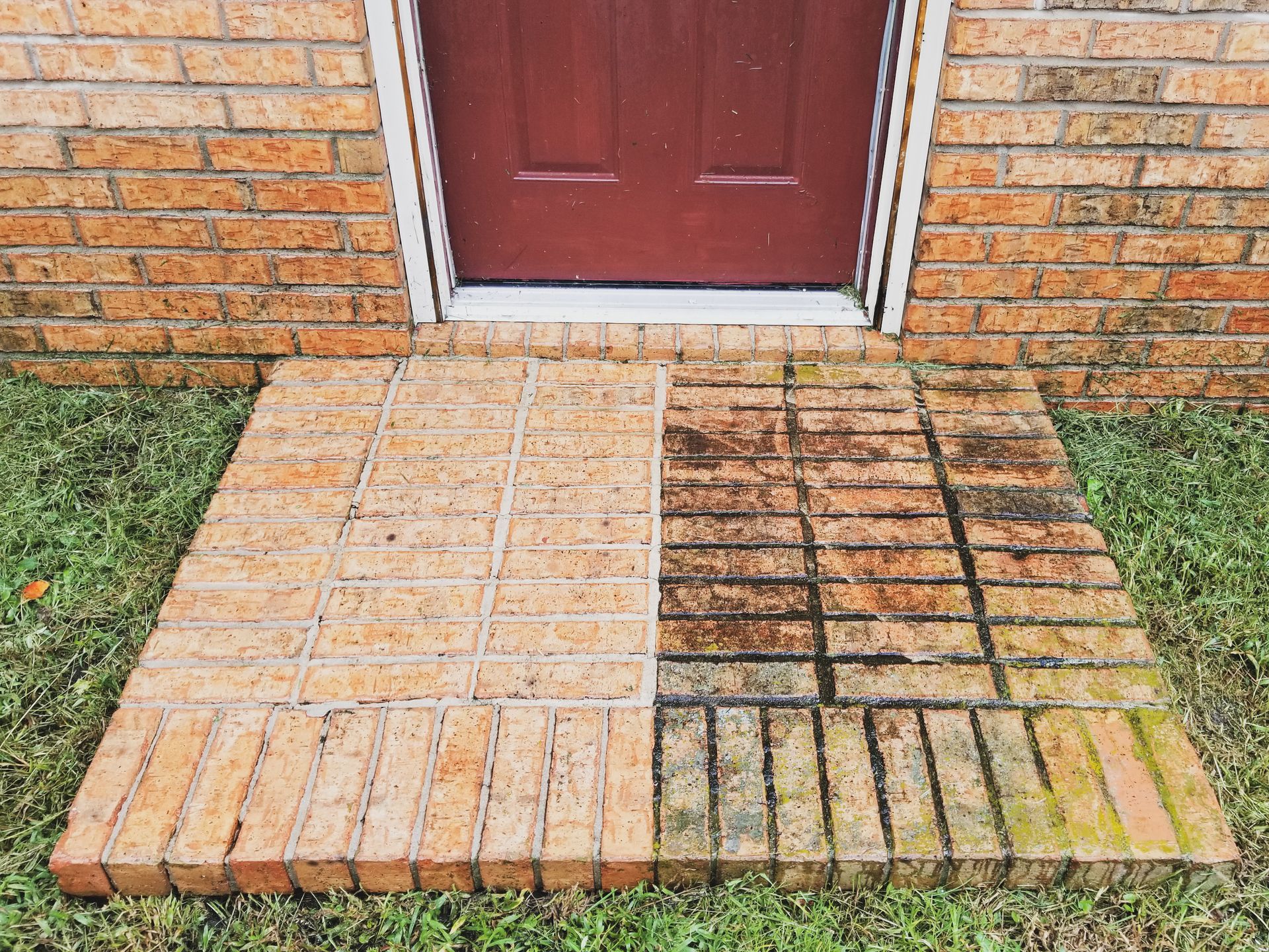 Brick walkway with contrasting clean and dirty pavers leading to a red front door.