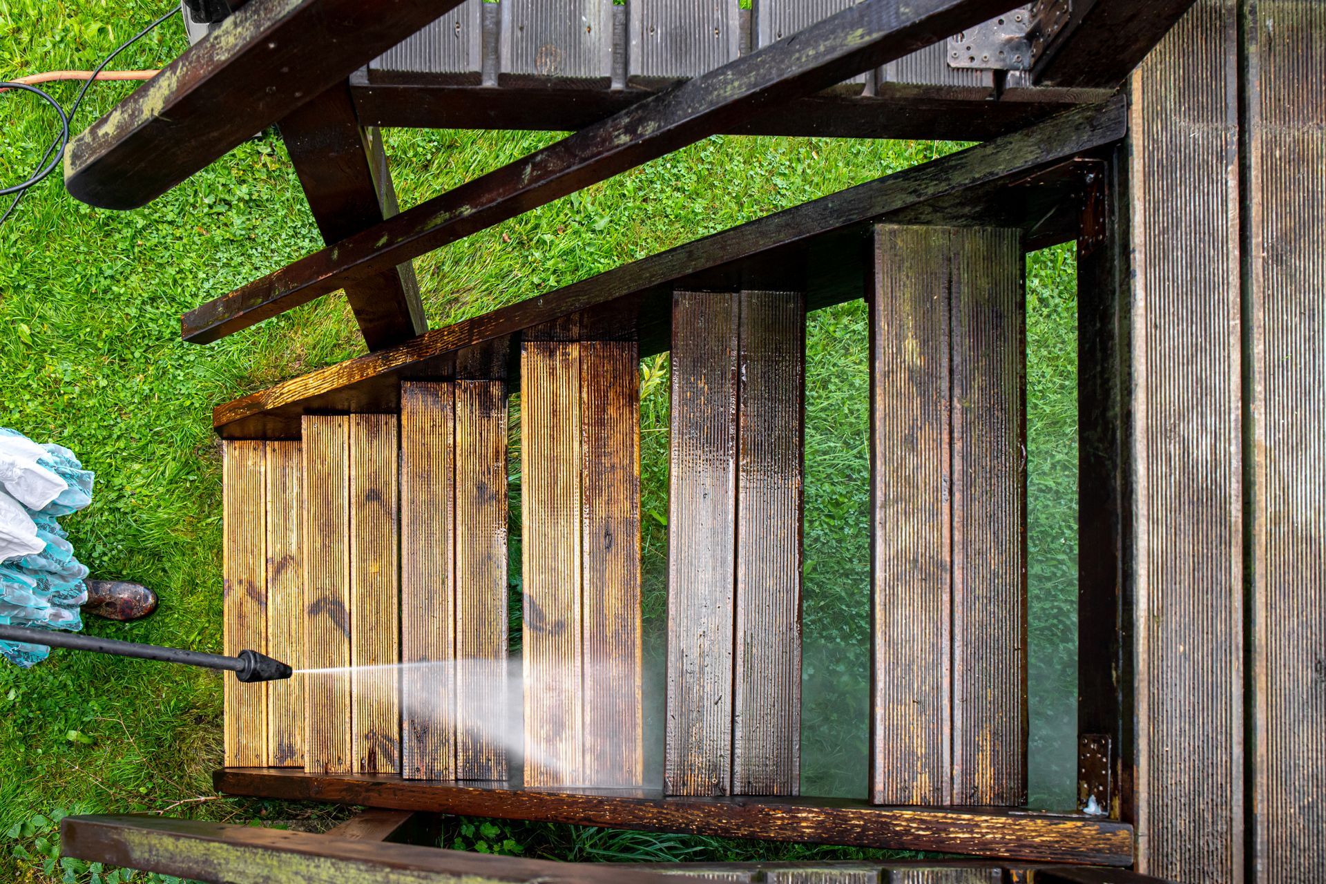 Wooden stairway descending through a grassy hillside, with a person’s legs visible at the left edge.