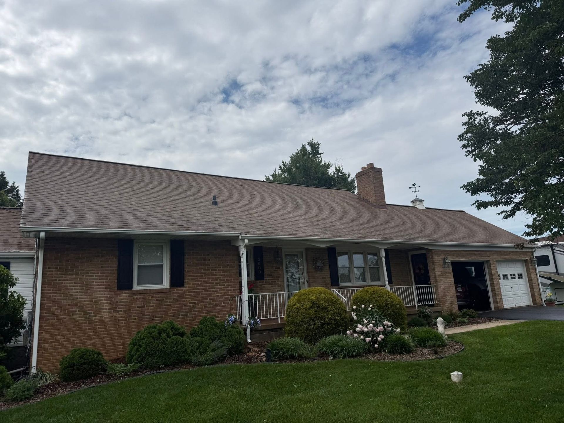 Person pressure-washing a dormer roof on a house, with water spray billowing upward.