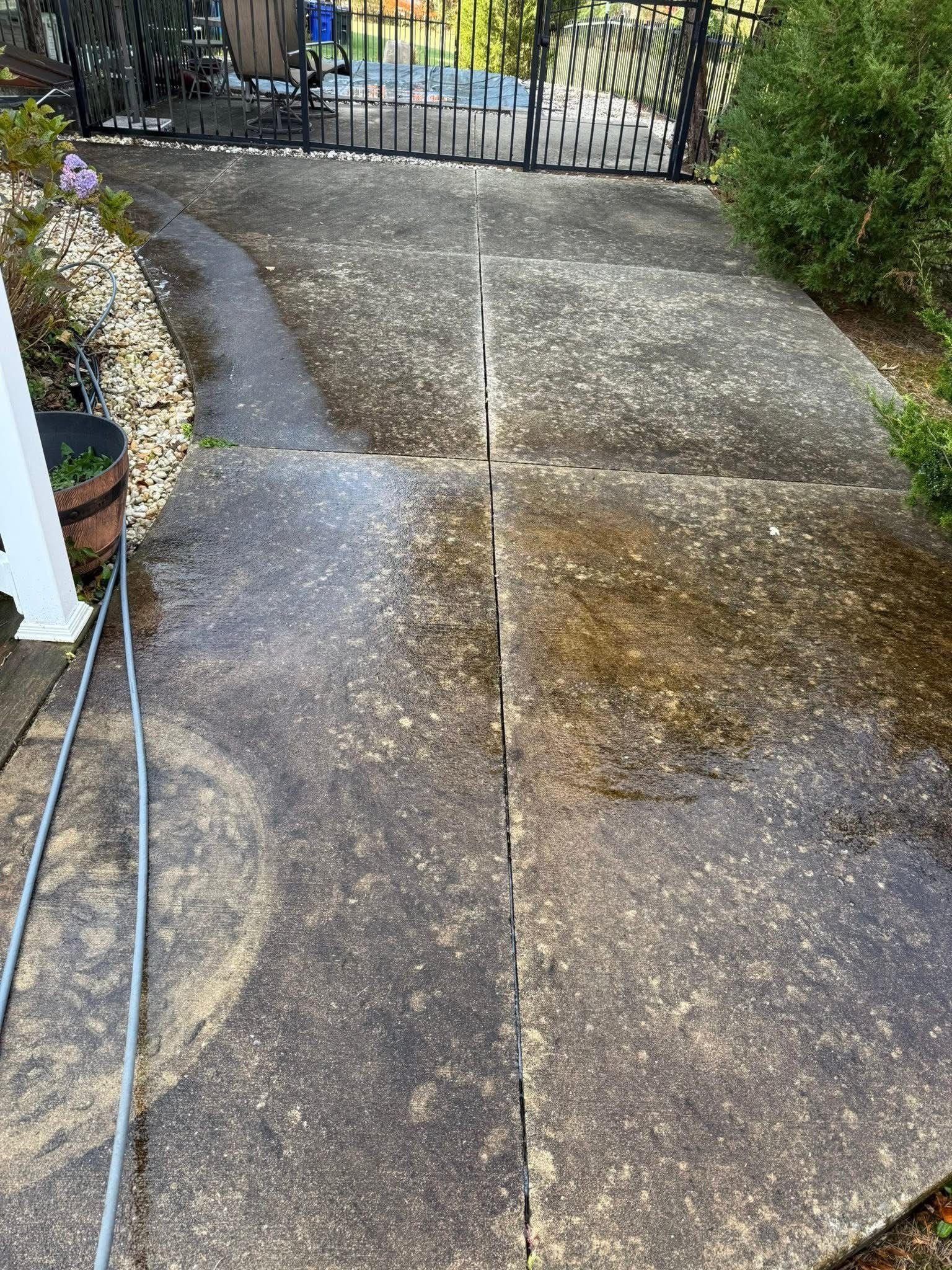 Power washing a brick patio beside a green lawn and path