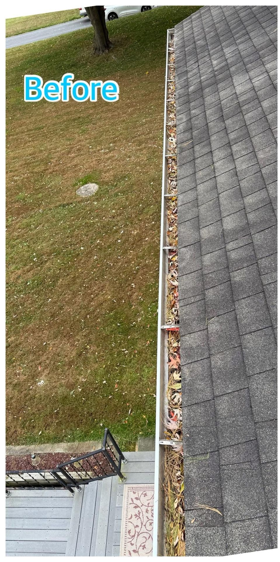 Worker pressure-washing a mossy red-tile roof beside a yellow house