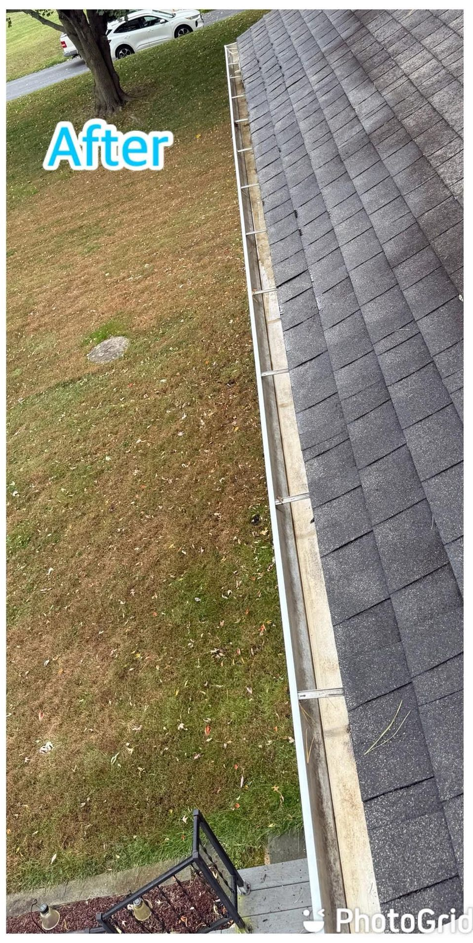 Worker power washing a red-tiled roof from a ladder