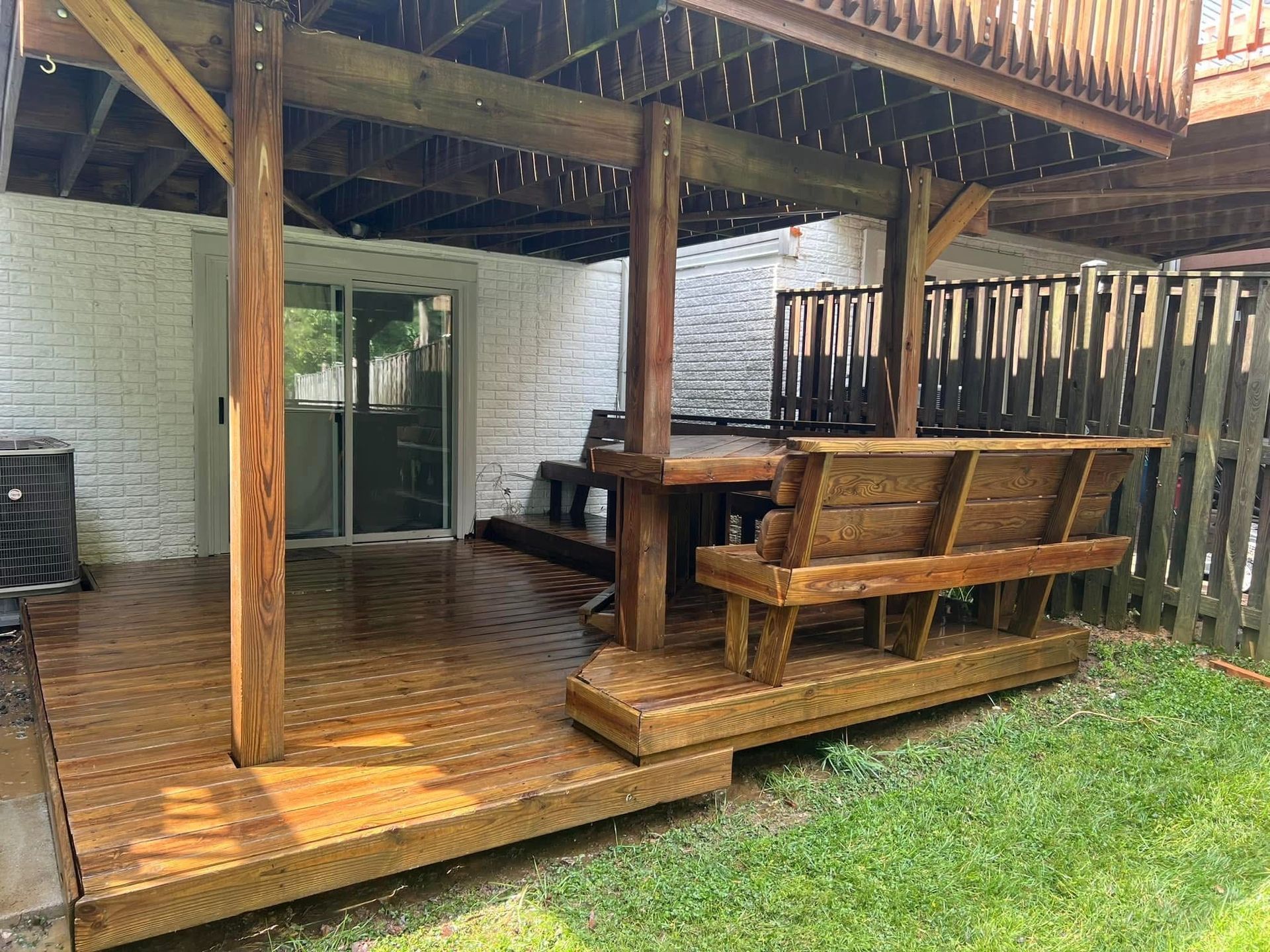 Person pressure-washing a wet wooden deck in warm sunlight
