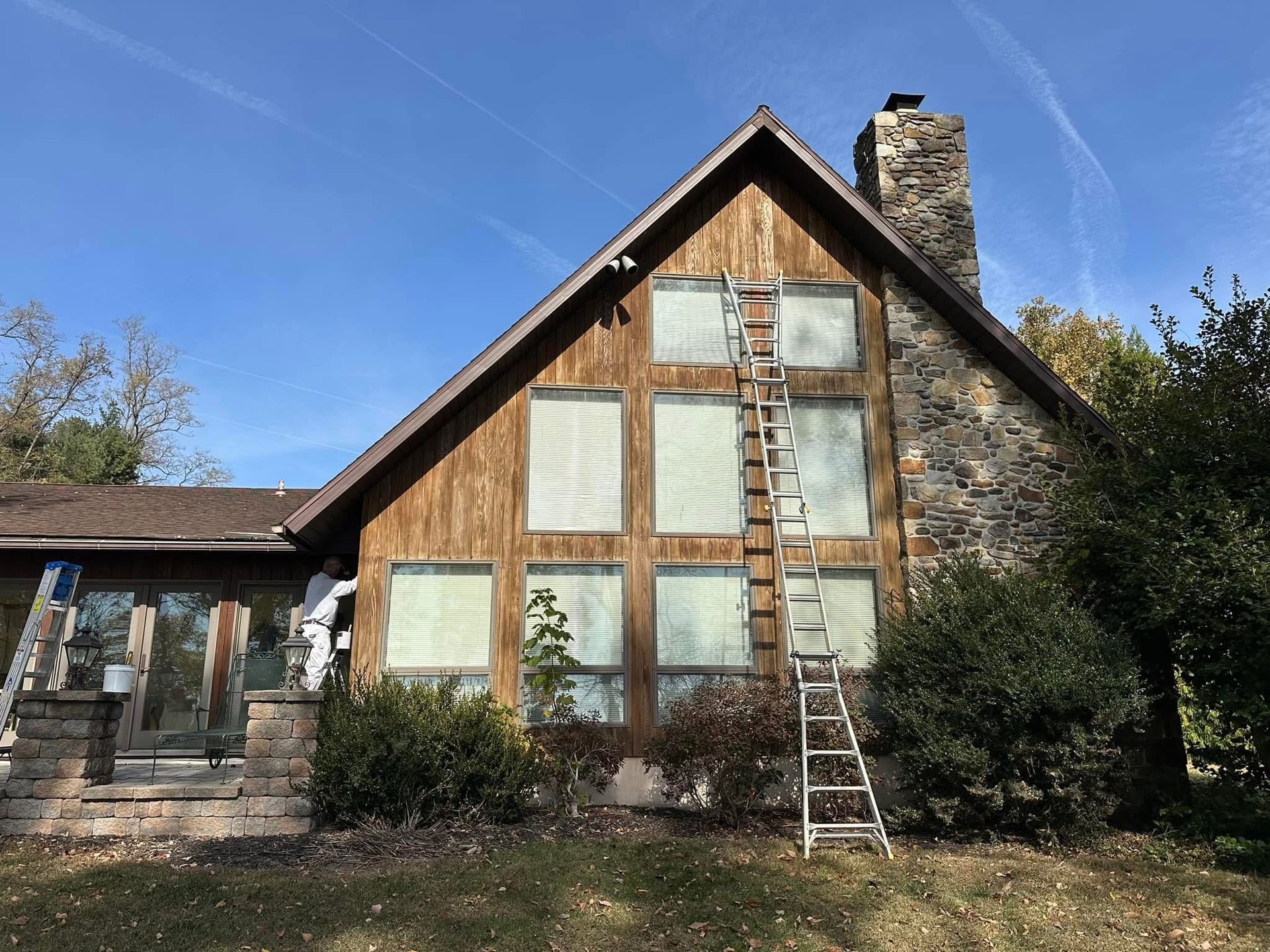 Pressure washer spraying a red house wall beside a window