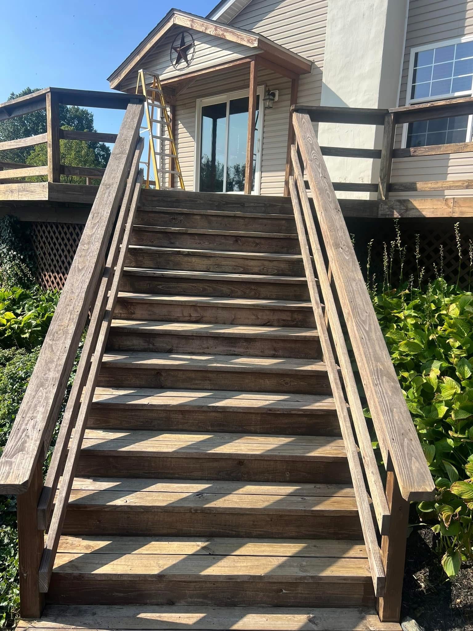 Pressure washer spraying water across a sunlit wooden deck, cleaning the surface.