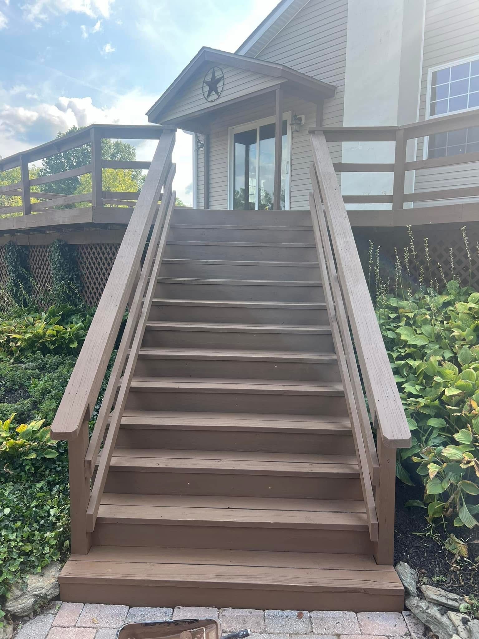 Pressure washing a wooden deck beside a gravel garden with green shrubs