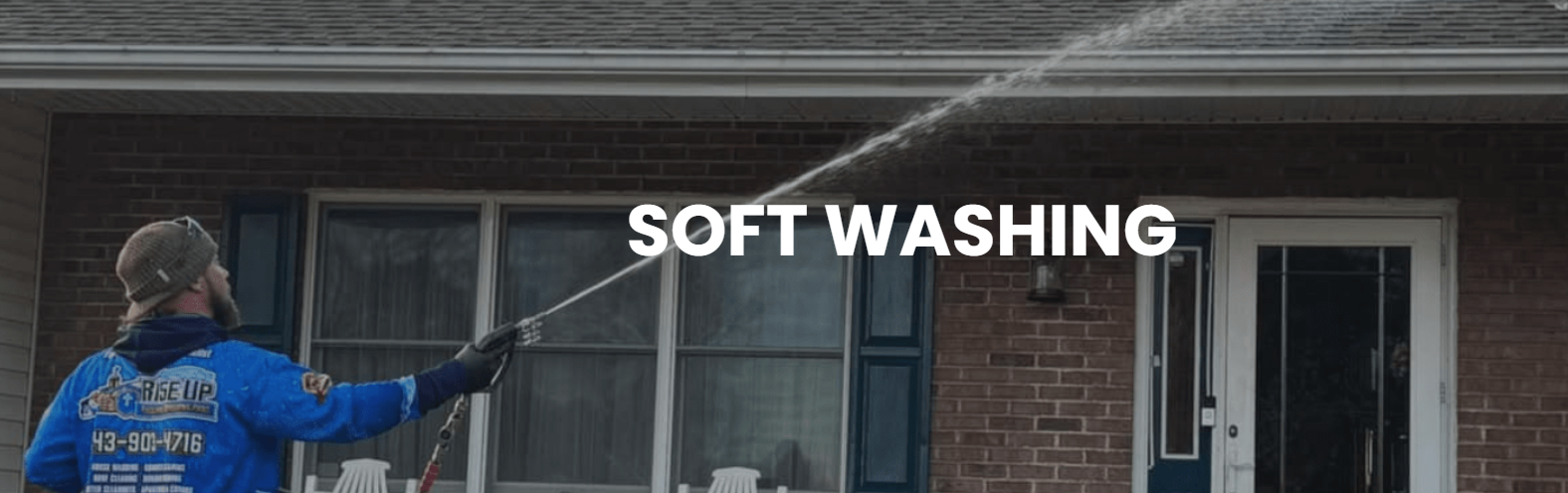 Person pressure-washing a cobblestone path beside a grassy park area