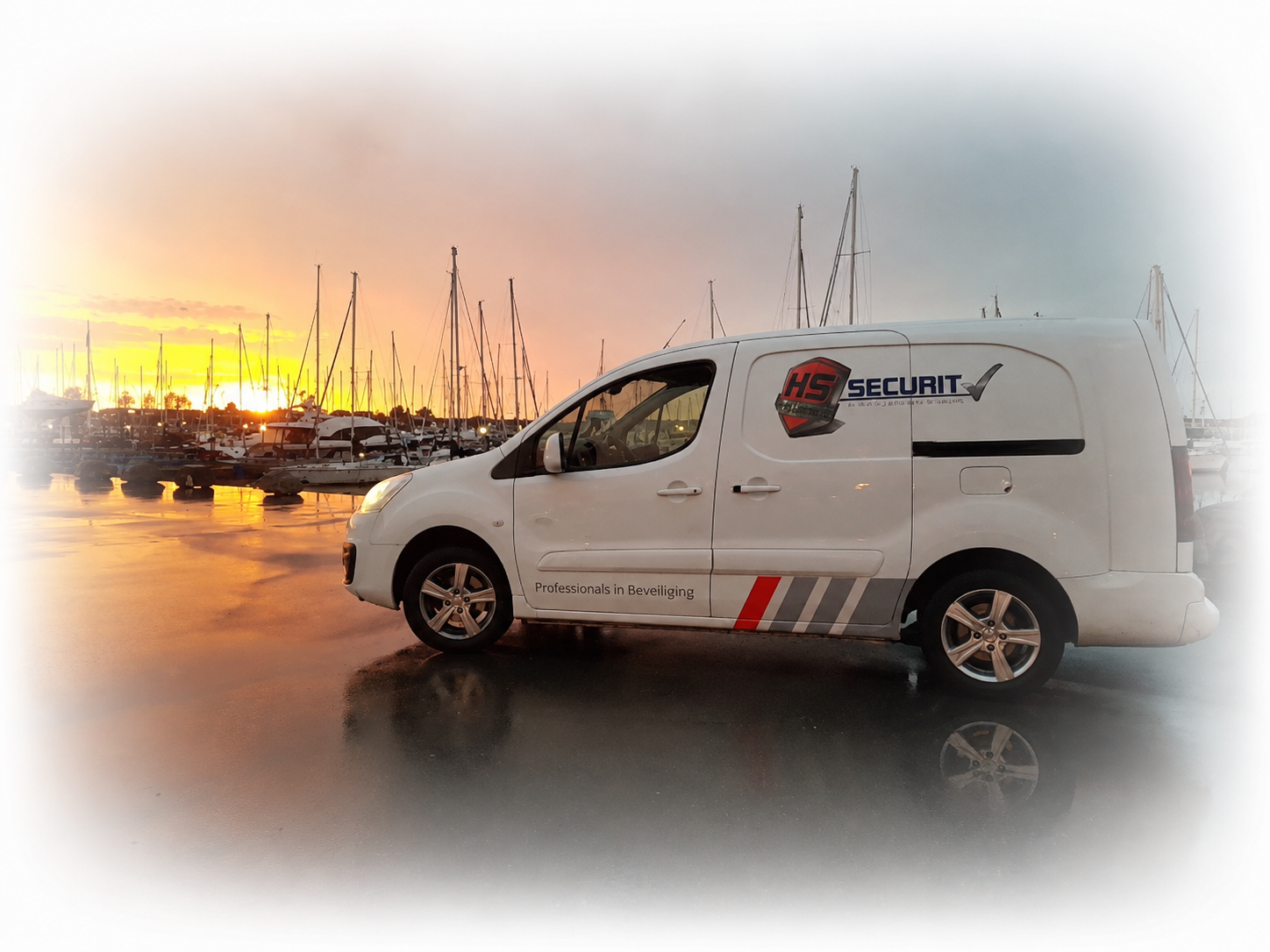 Een witte beveiligingswagen staat geparkeerd bij een jachthaven bij zonsondergang, met boten en masten op de achtergrond.