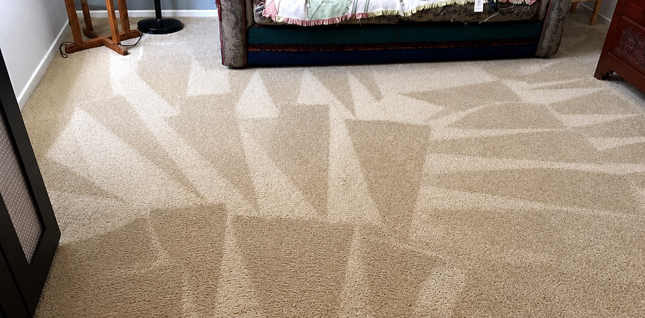 Beige carpet with sunlight shadows in a room, with sofa edges visible at the top