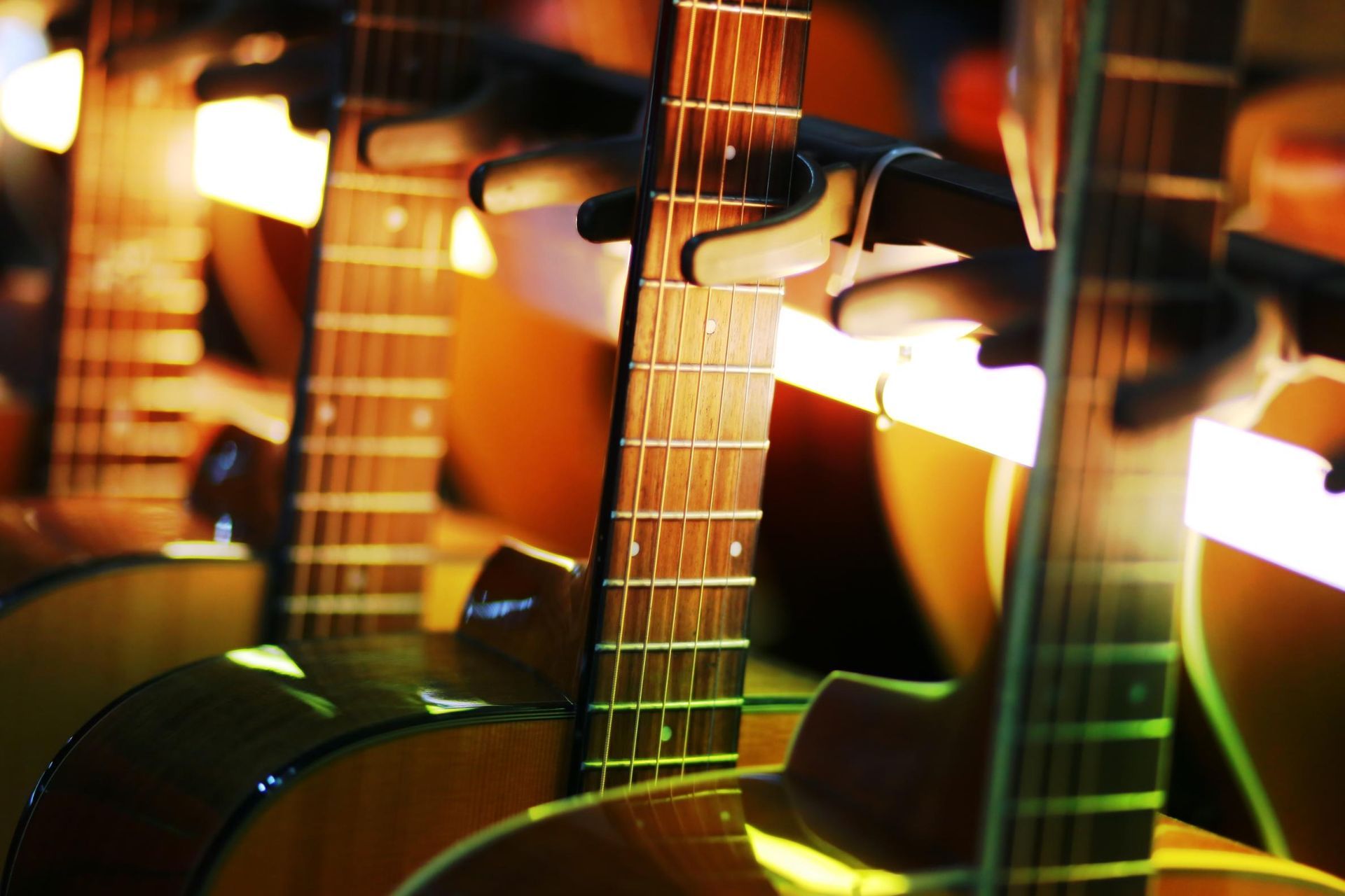 Close-up of acoustic guitars on display under warm orange stage lights