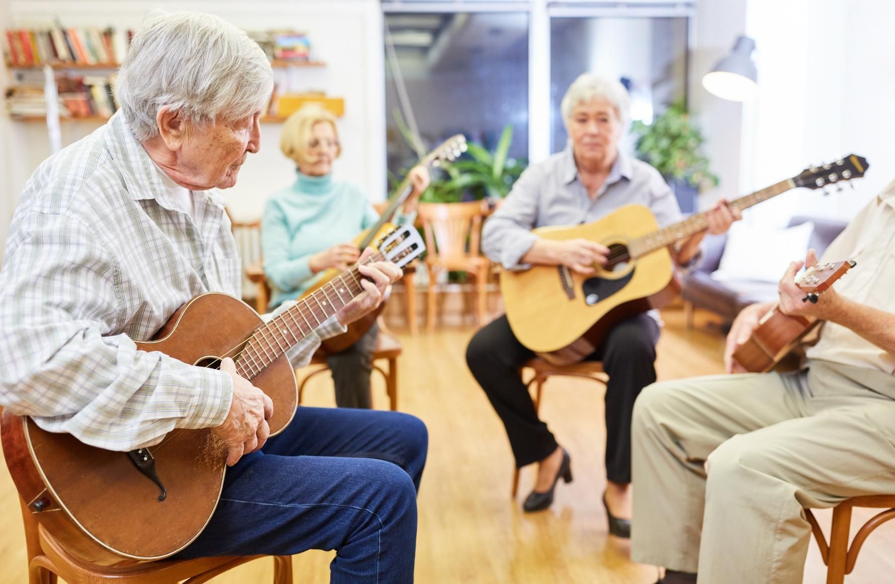 Musicians playing guitars in a bright community room during a small group session