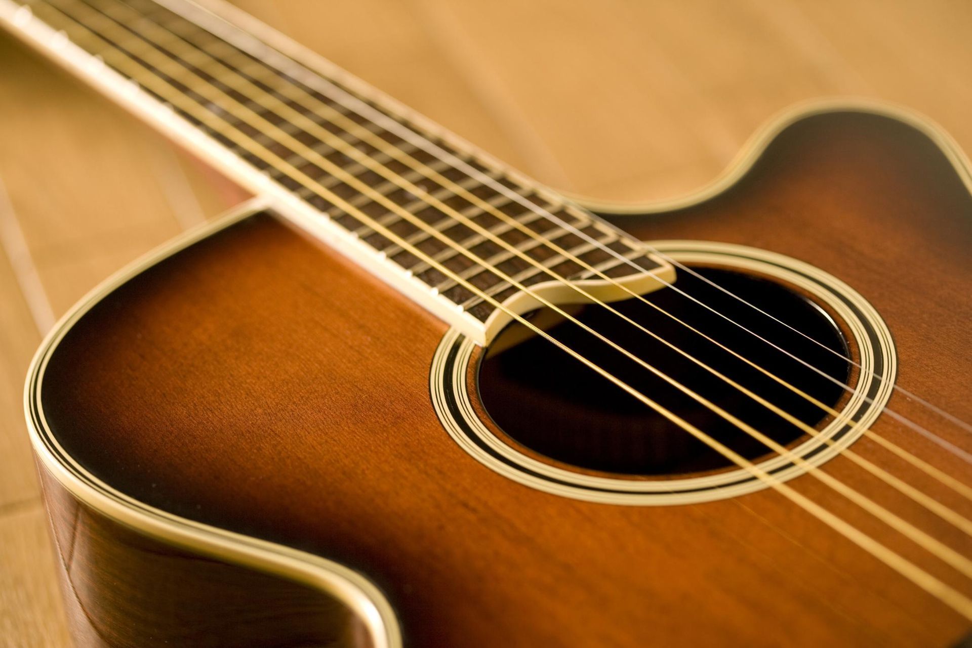 Close-up of a brown acoustic guitar with strings and sound hole in warm light