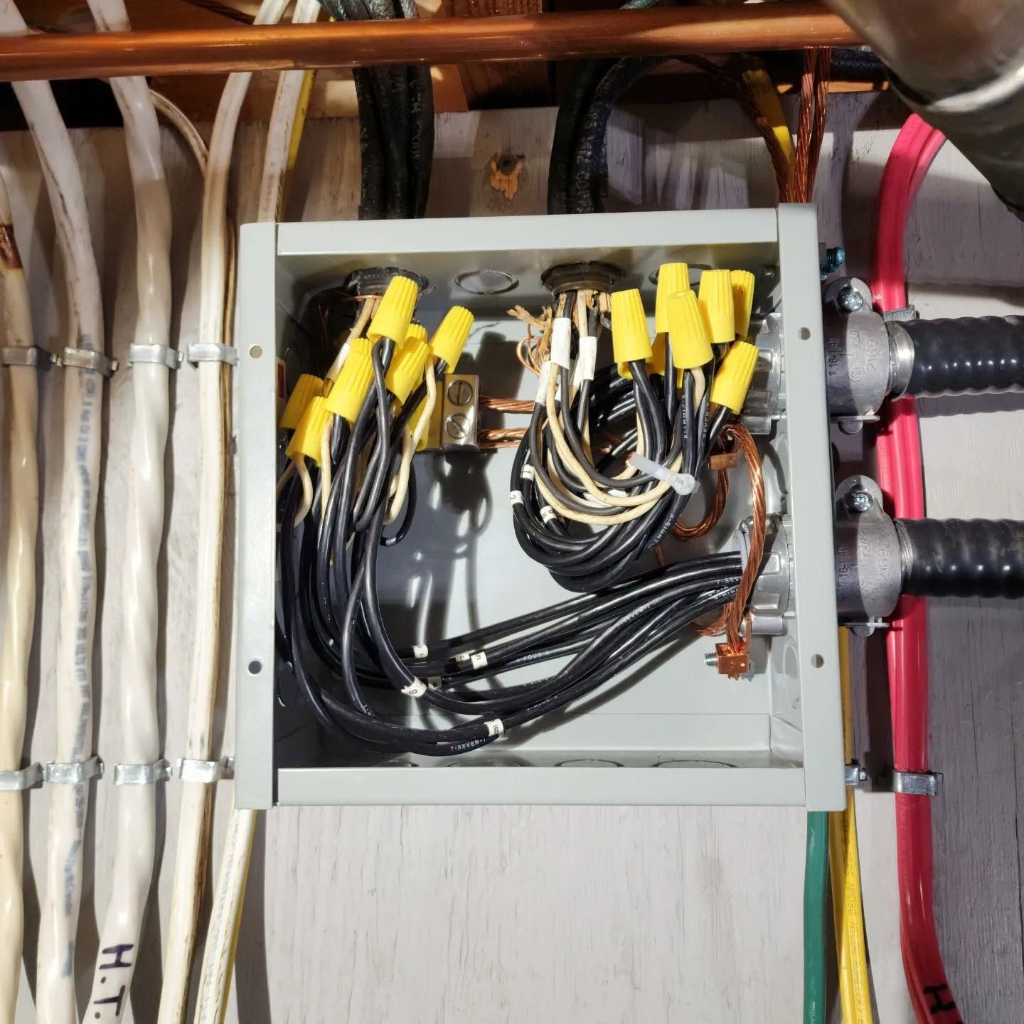 Open electrical junction box with black and white wires and yellow wire connectors on a wall.