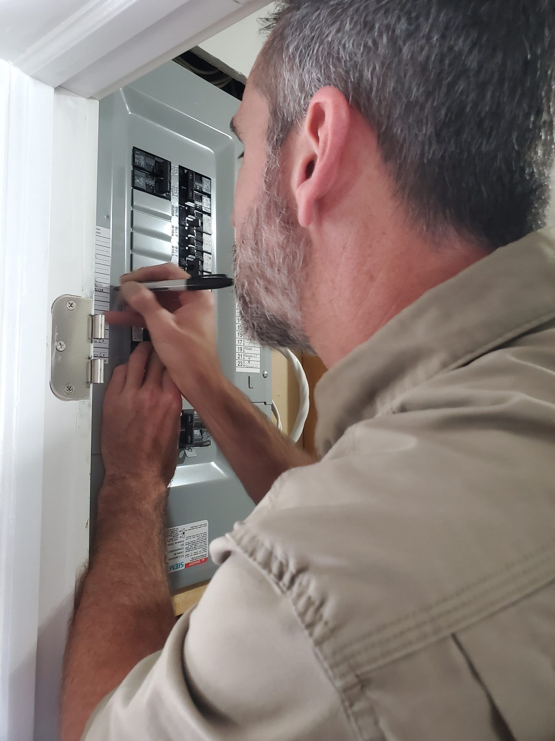 Technician wiring an electrical panel inside a wall cabinet