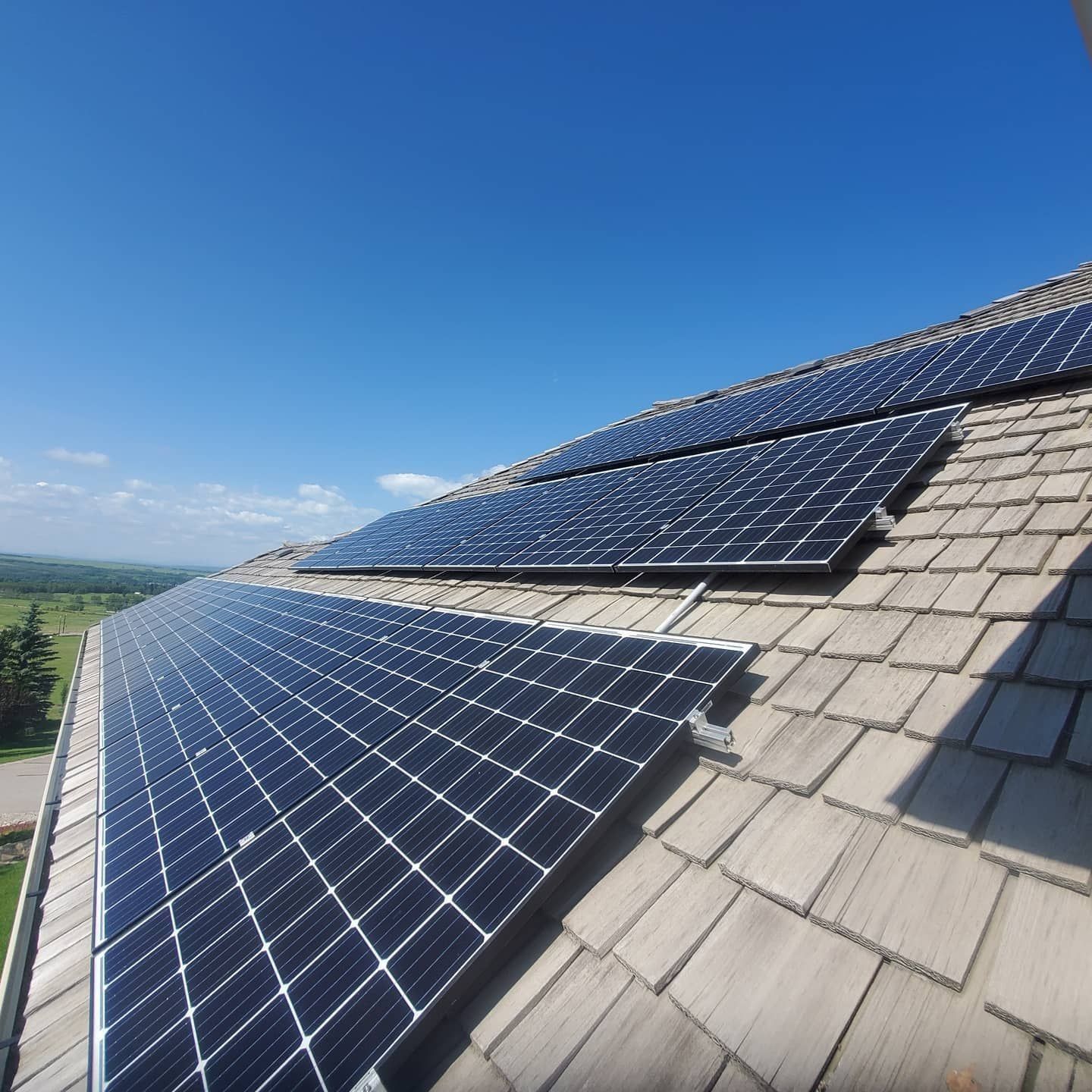 Solar panels mounted on a shingled rooftop under a clear blue sky