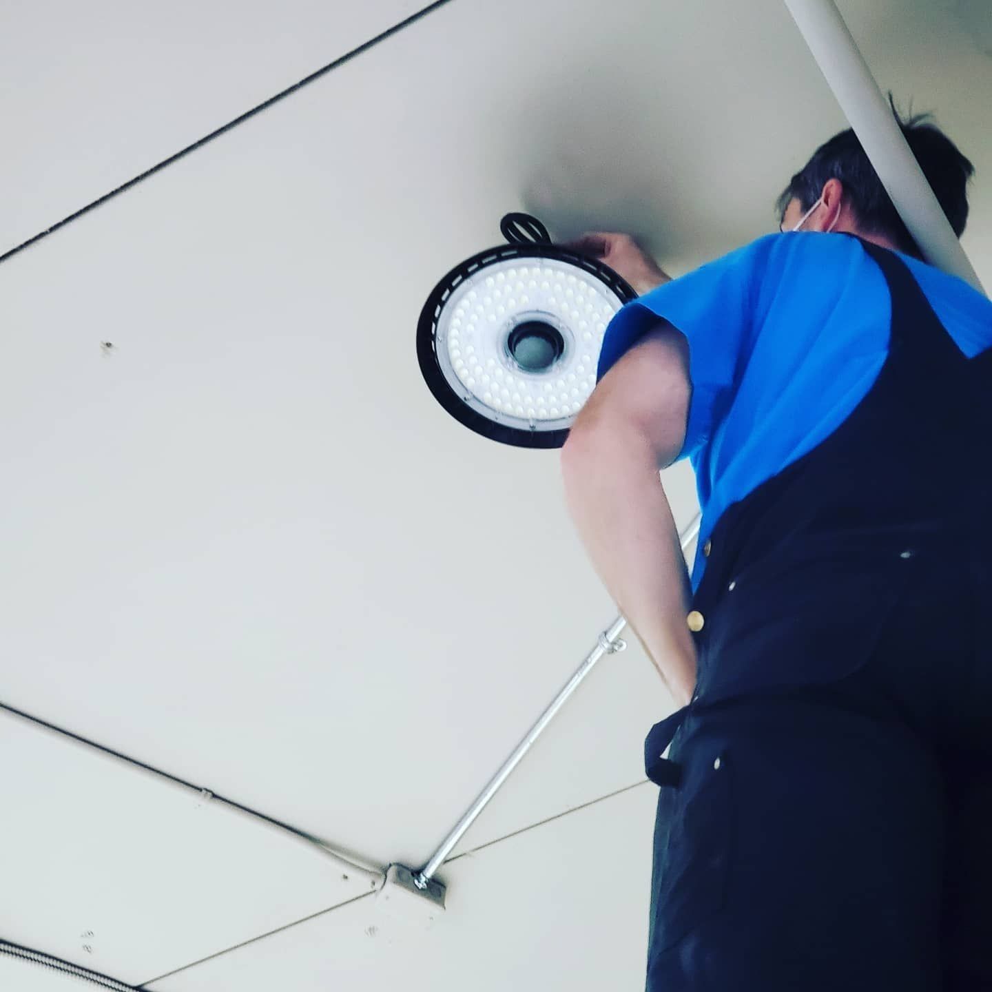 Person in a blue shirt replacing a ceiling light fixture.