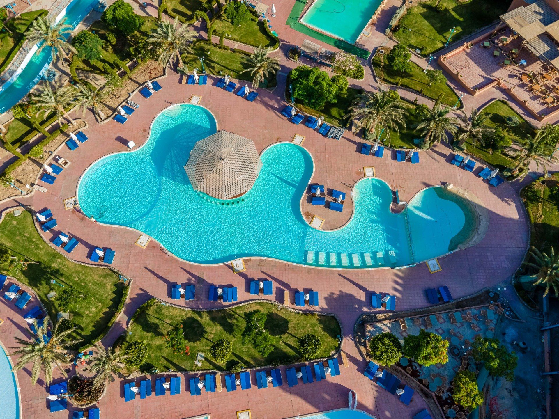 An aerial view of a large swimming pool surrounded by chairs and palm trees