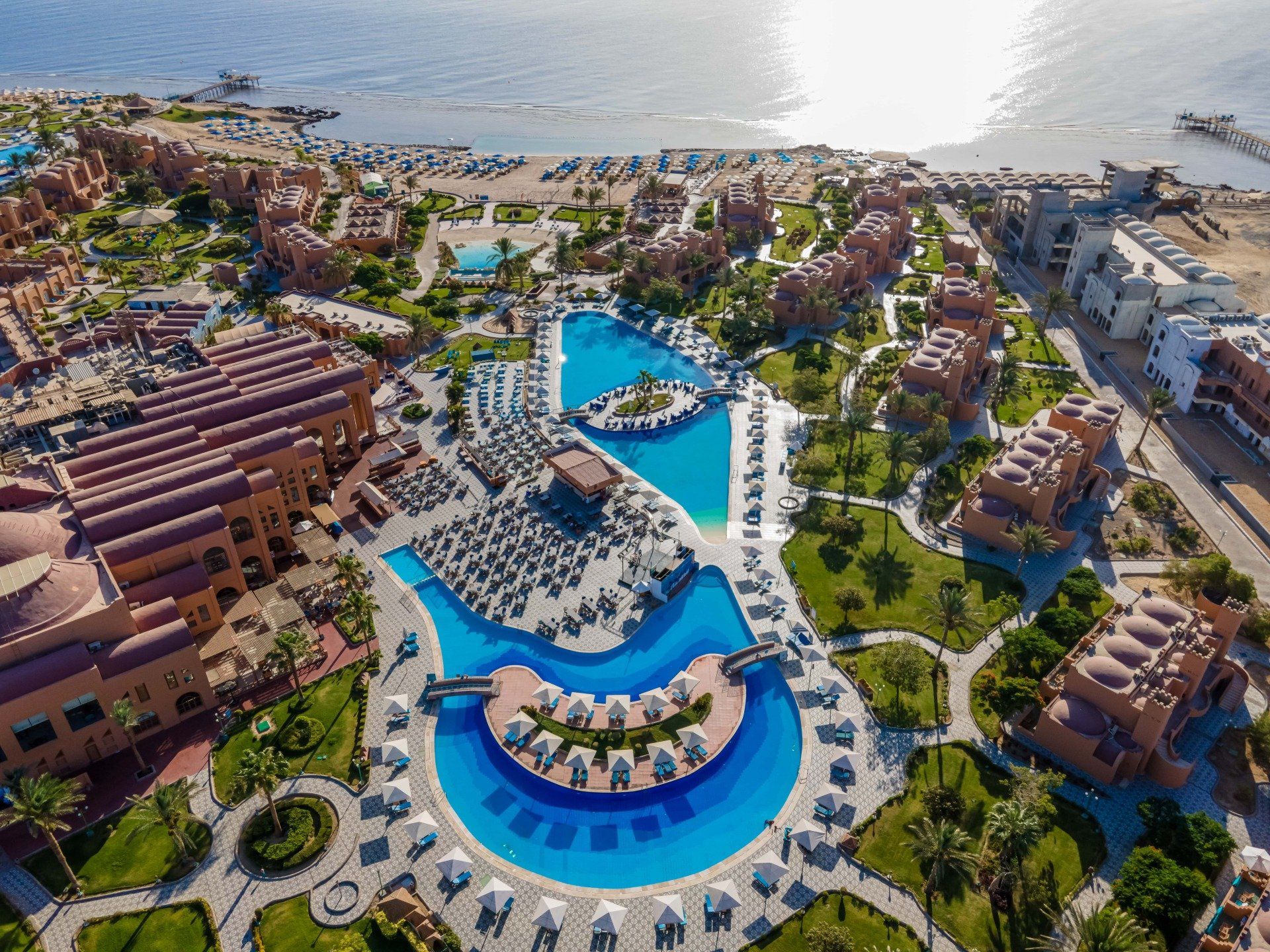 An aerial view of a large resort with a large pool surrounded by buildings.