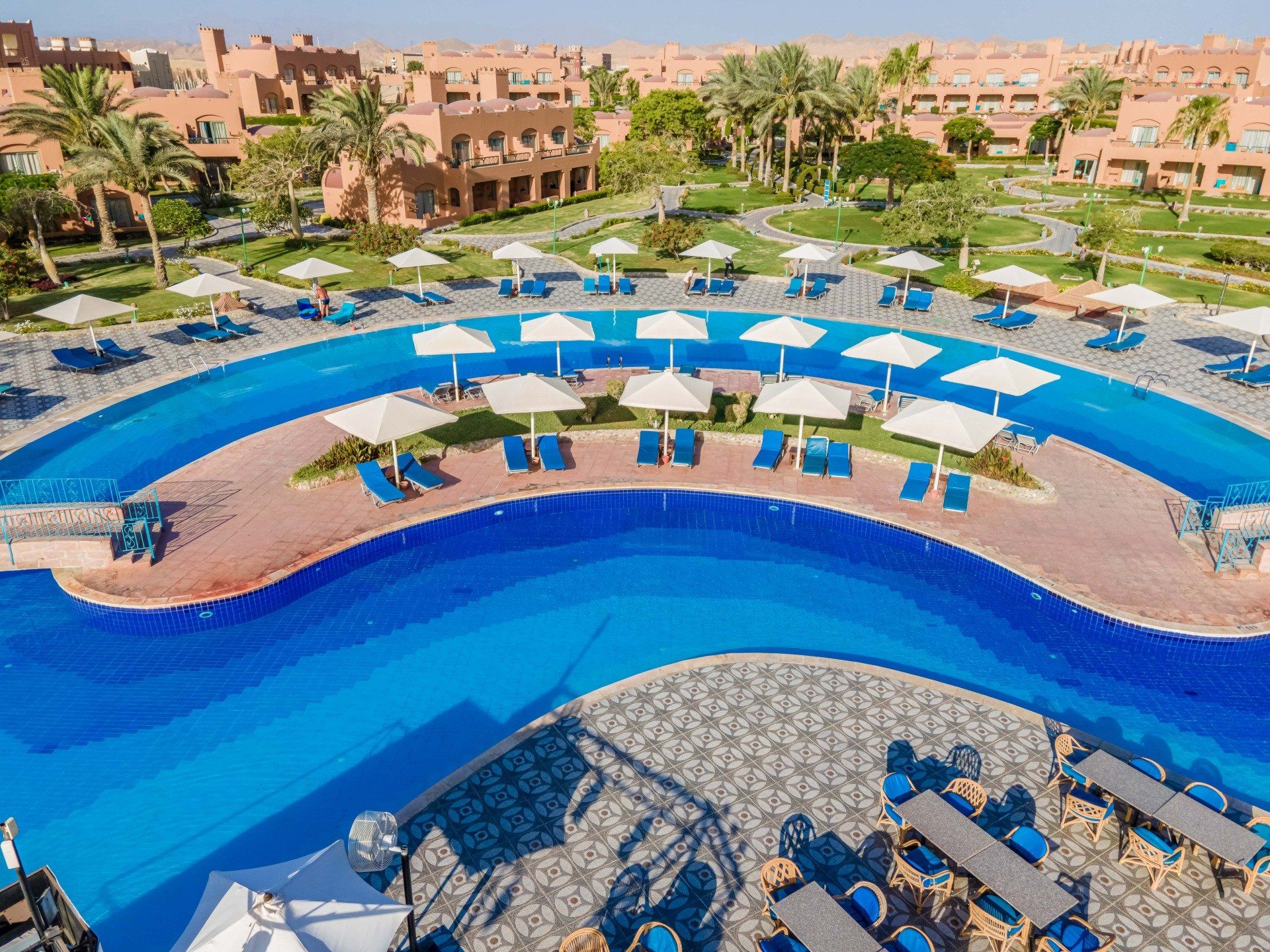 An aerial view of a large swimming pool surrounded by tables and chairs.