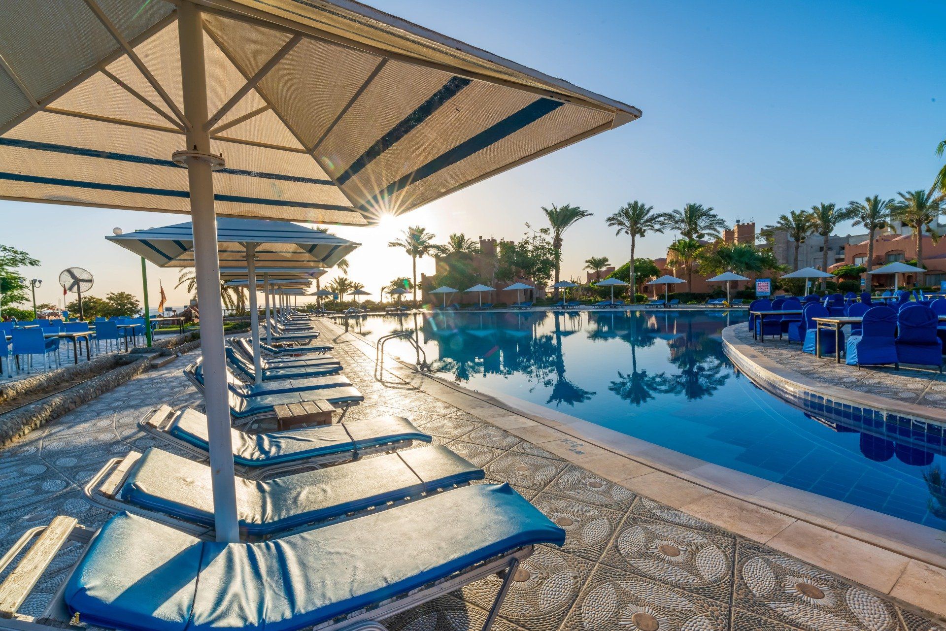 A swimming pool surrounded by chairs and umbrellas at a resort.