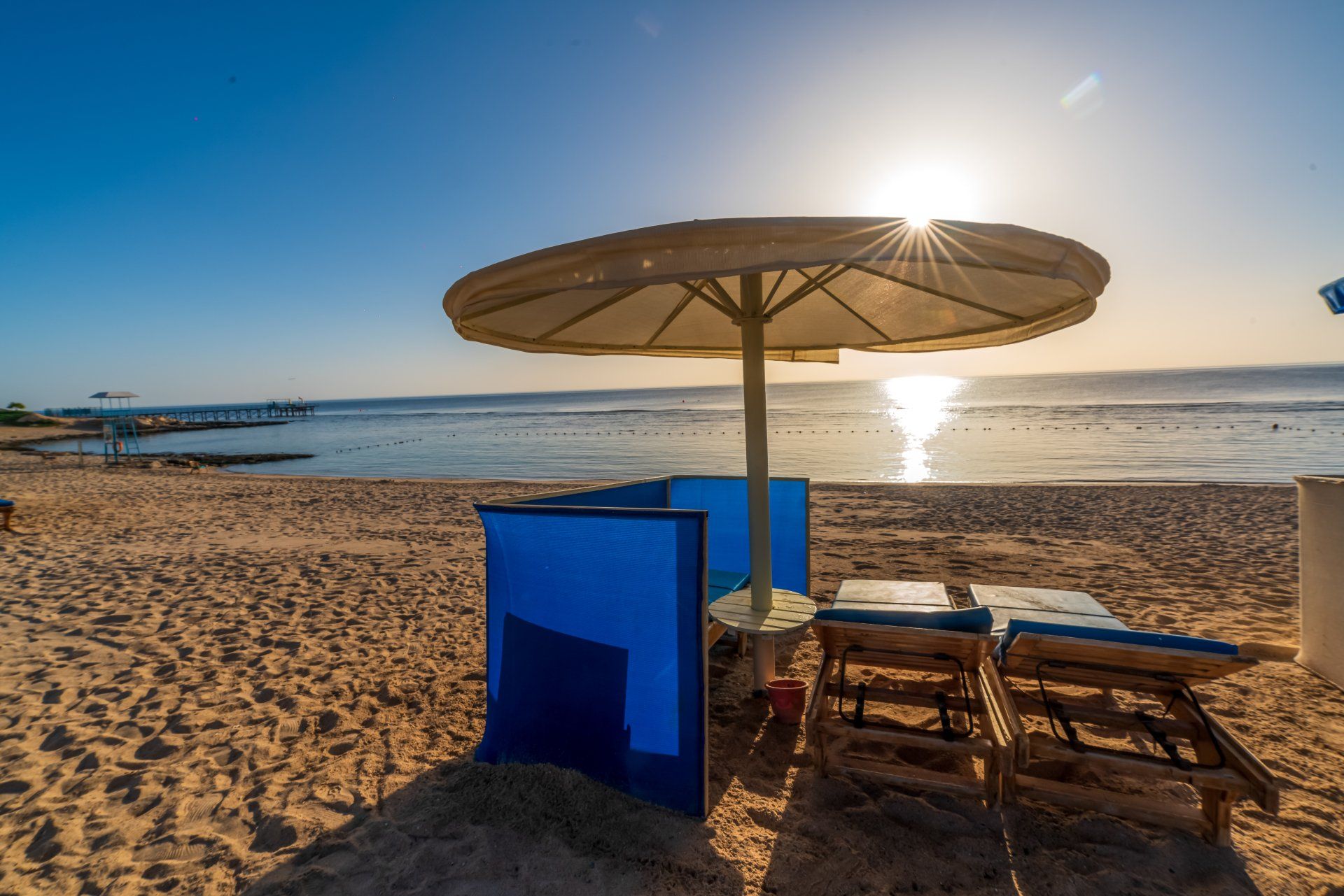 The sun is shining through the umbrella on the beach.