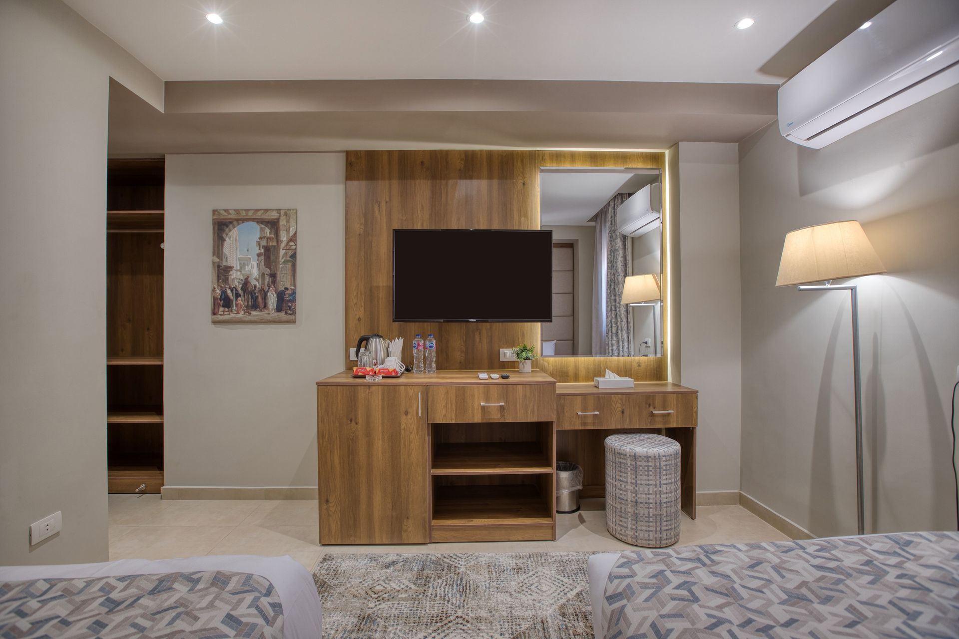A hotel room with two beds , a television , a dresser and a mirror.